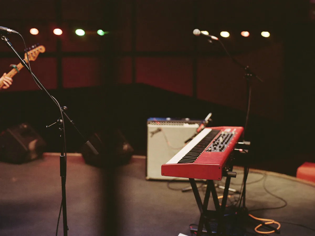 Bühne mit rotem Keyboard, Mikrofonen und Gitarre vor dem Auftritt